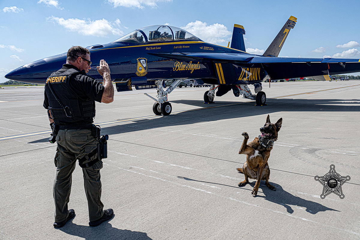 K9 Vero salutes his handler, Capt. DeBolt, in front of a Blue Angels plane